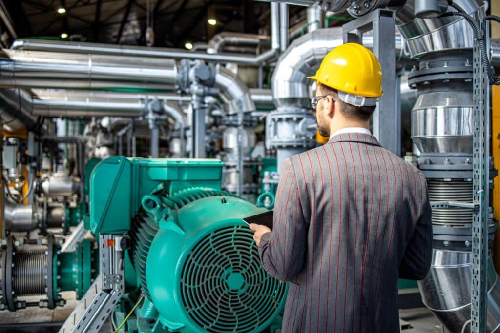 Engineer in a hard hat inspecting industrial equipment with integrated hydrogen sensor technology for safety monitoring.