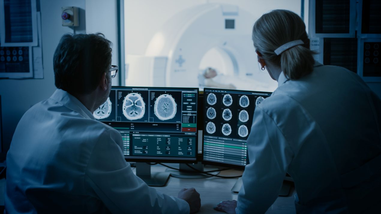 Zwei Fachleute werten MRT-Aufnahmen in der Radiologie Duesseldorf aus, waehrend der Patient im Scanner liegt