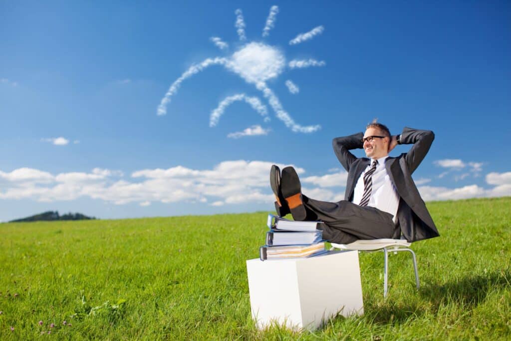 Manager entspannt auf Wiese mit Sonne aus Wolken