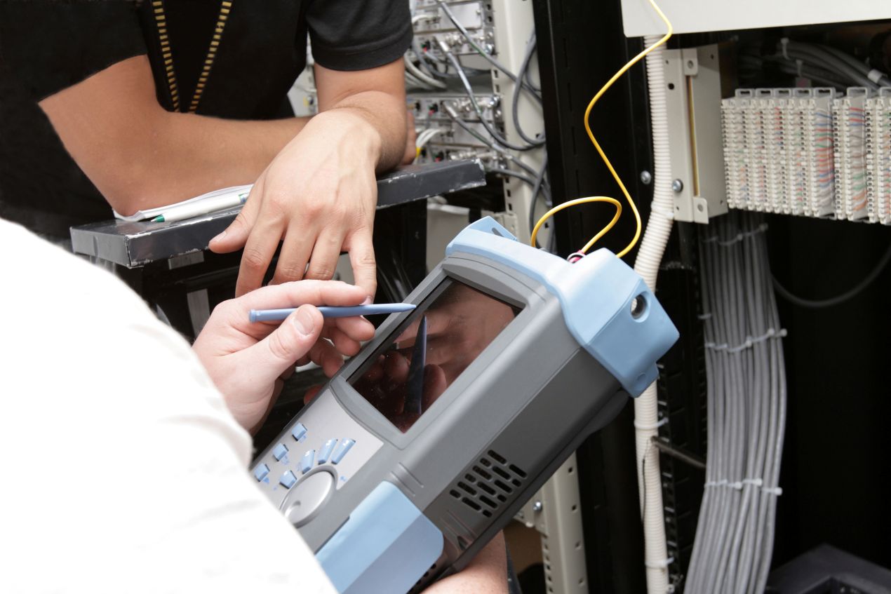 Messdienstleistung im Einsatz – Fachkräfte prüfen Netzwerktechnik mit professionellem Messgerät für präzise Signalqualität
