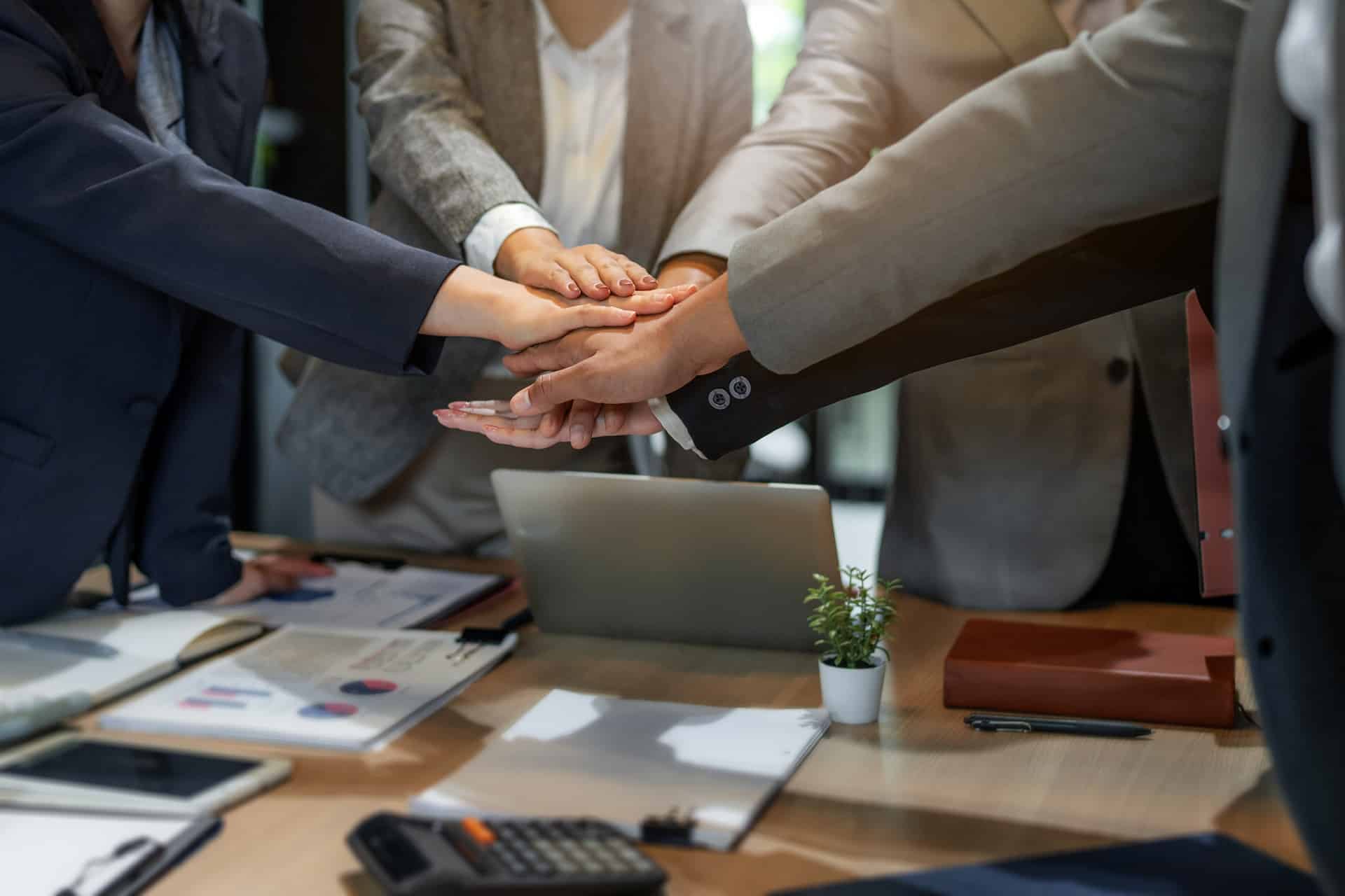 Team legt Hände zusammen im Büro | Arbeitsschutz E-Learning