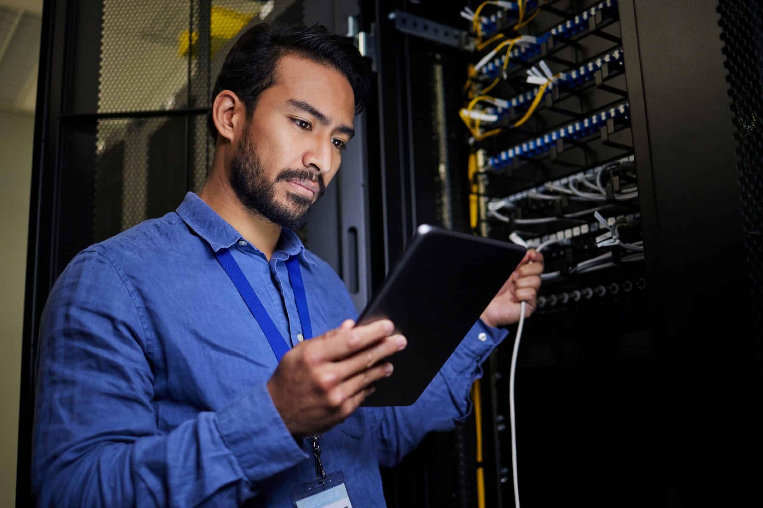 Techniker kontrolliert Verbindungen in Serverraum und überwacht Dateninfrastruktur in industrieller Fertigung