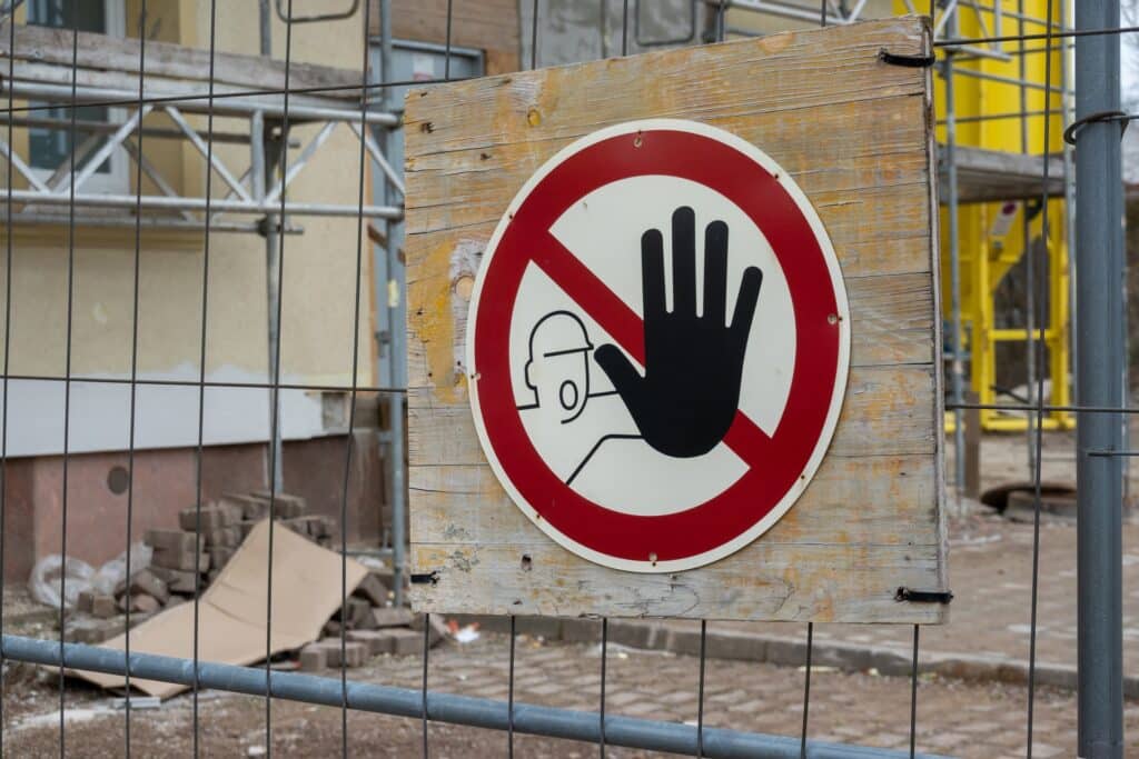 Stopp-Warnschild auf Holzplatte vor Gerüst | Bauzaun