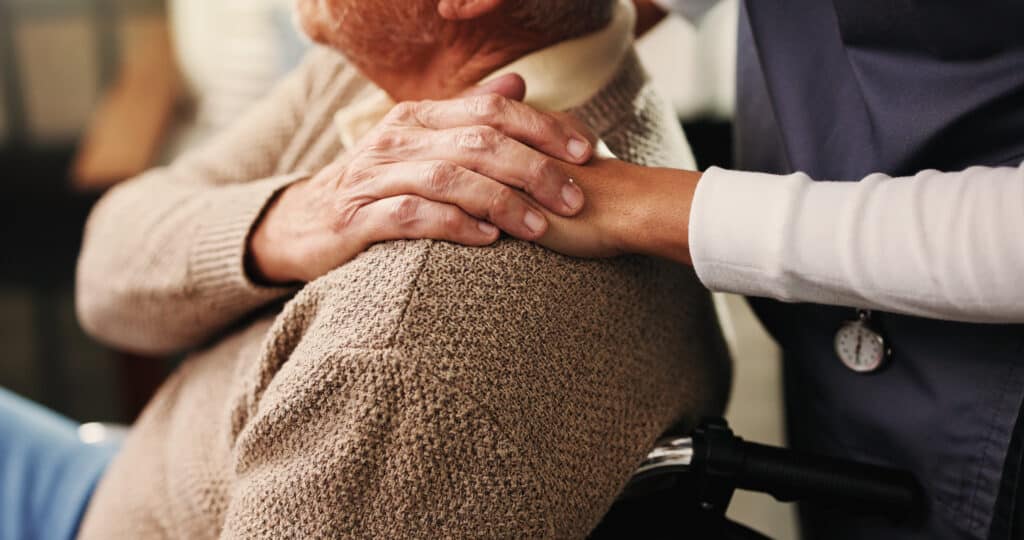 Pflegekraft hält Hand eines Senioren
